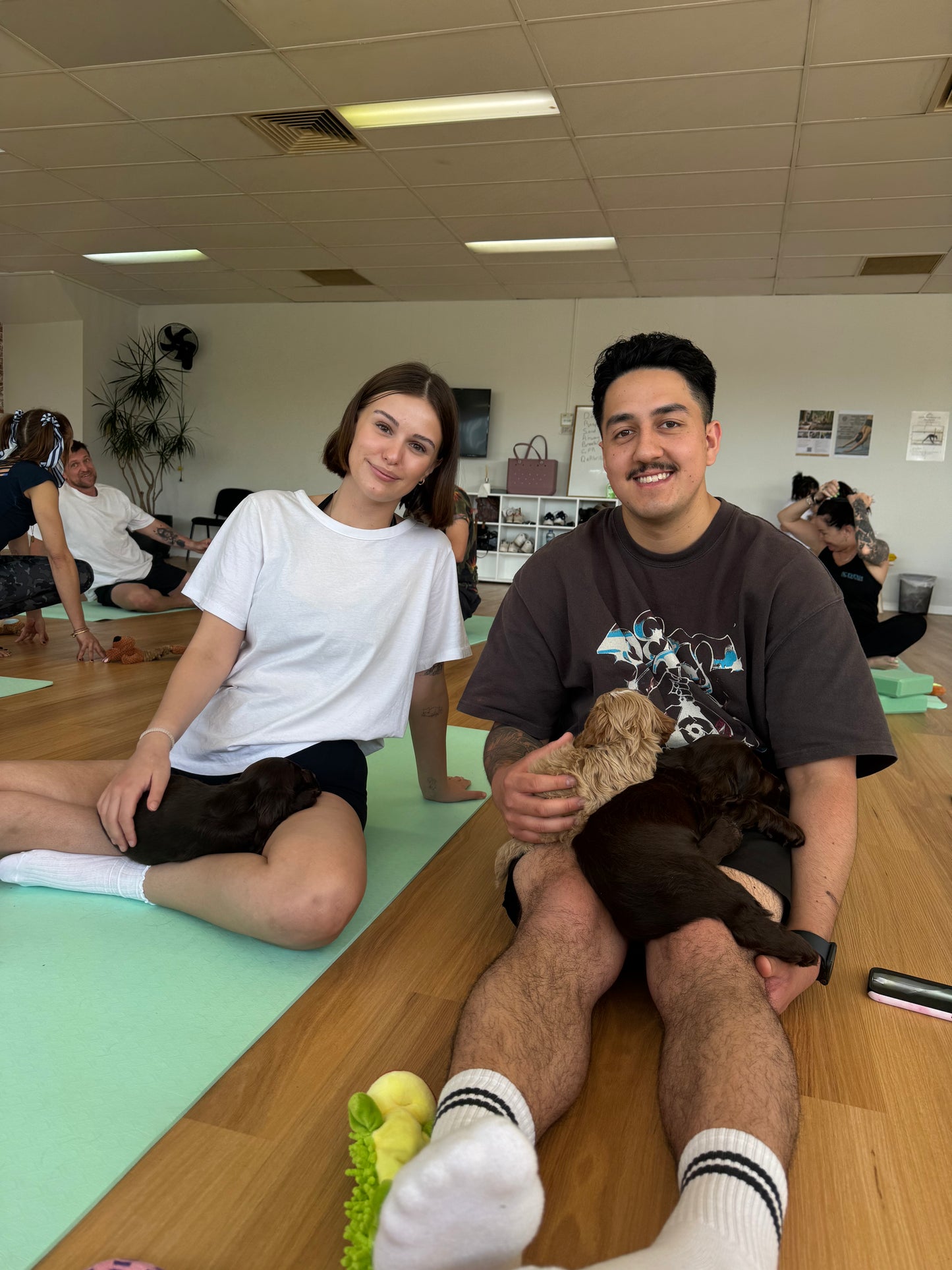 Couple relaxing with puppies during a Yogi Paws puppy yoga class on the Central Coast NSW