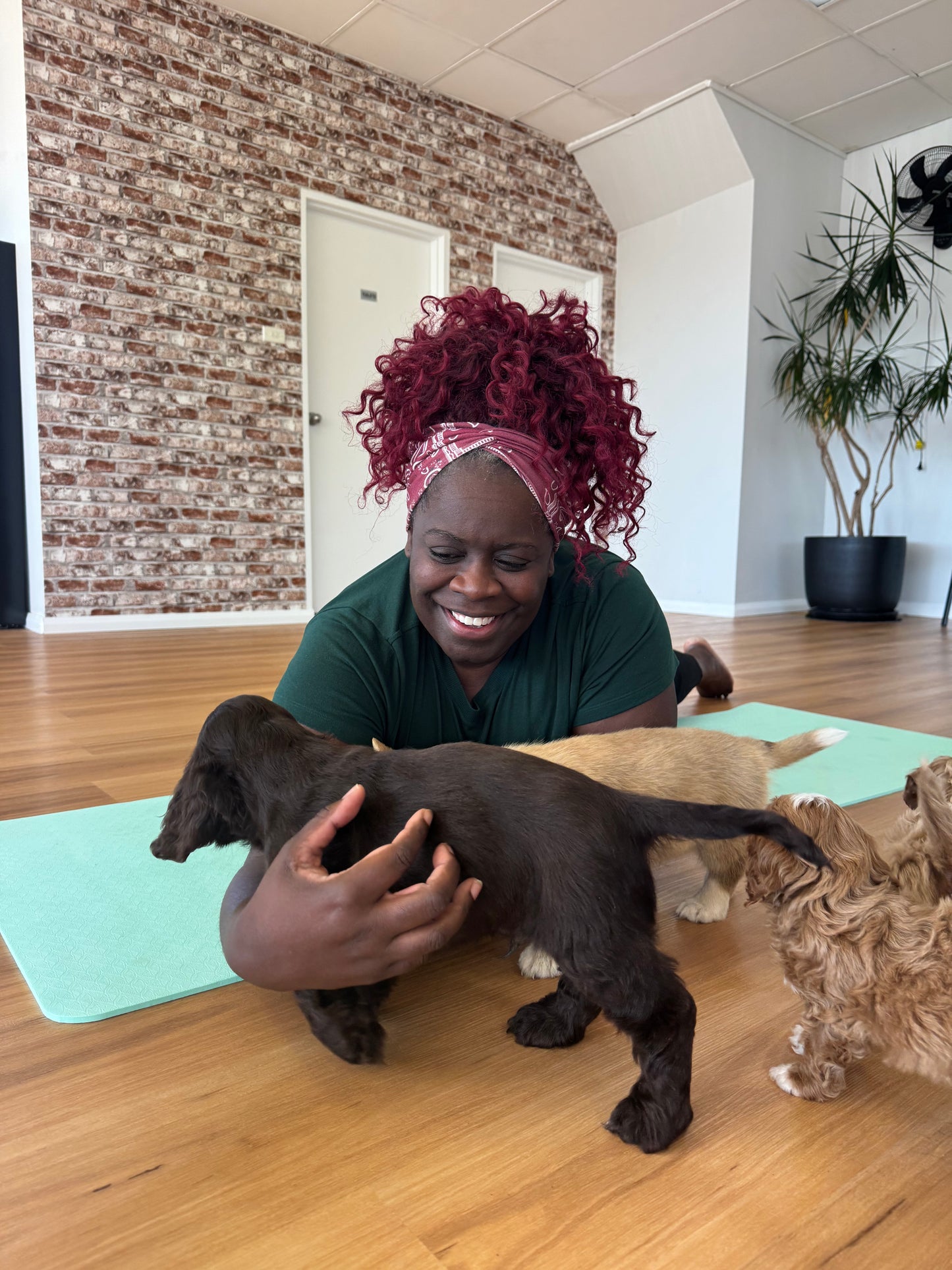 Woman smiling while playing with puppies during a Yogi Paws puppy yoga class on the Central Coast NSW