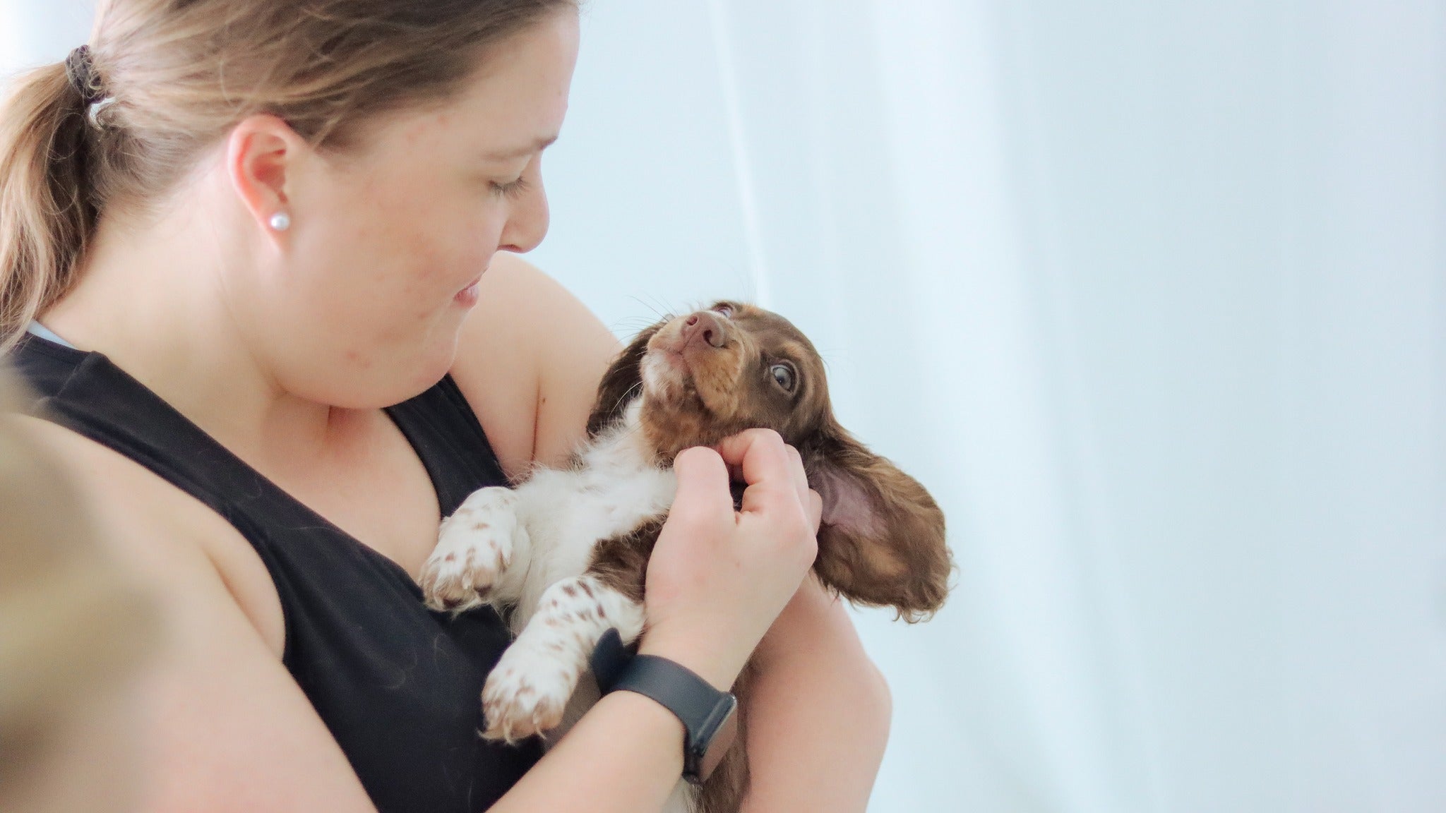 Participant cuddling a puppy during Yogi Paws Puppy Yoga class in Australia on the Central Coast