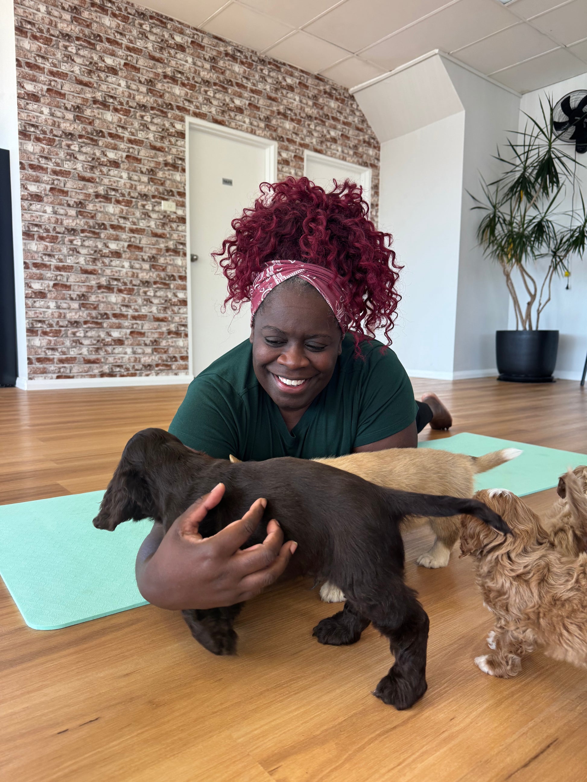 Woman smiling while playing with puppies during a Yogi Paws puppy yoga class on the Central Coast NSW